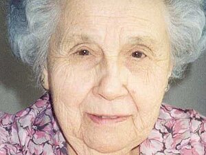 Pauline Mach Ältere Dame mit Dauerwelle lächelt leicht in die Kamera