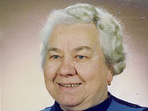 Maria Tucek Eine ältere Dame mit weißer Dauerwelle lächelt freundlich, sie blickt an der Kamera vorbei