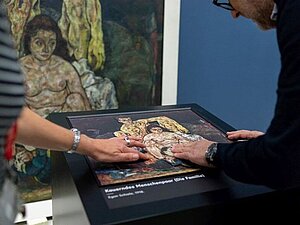 Ein Mann und eine Frau Tasten das Tastrelief des Gemäldes von Egon Schiele ab.