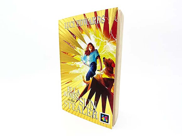 Ein Buch mit dem Titel „Ella Jones vs the Sun Stealer“ von Lucy Edwards. Auf dem Cover stehen ein Mädchen und ein Hund vor einem Hintergrund aus gelben Strahlen und Blitzen.