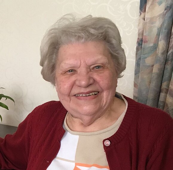 Anna Huber hatte selbst eine Sehbehinderung. Ältere Frau mit grauen Haaren und weinroter Jacke lächelt in die Kamera