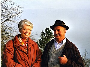 Dr. Margaretha Berghaus Ein älteres Pärchen steht nebeneinander in einer Herbstlandschaft, beide lächeln in die Kamera